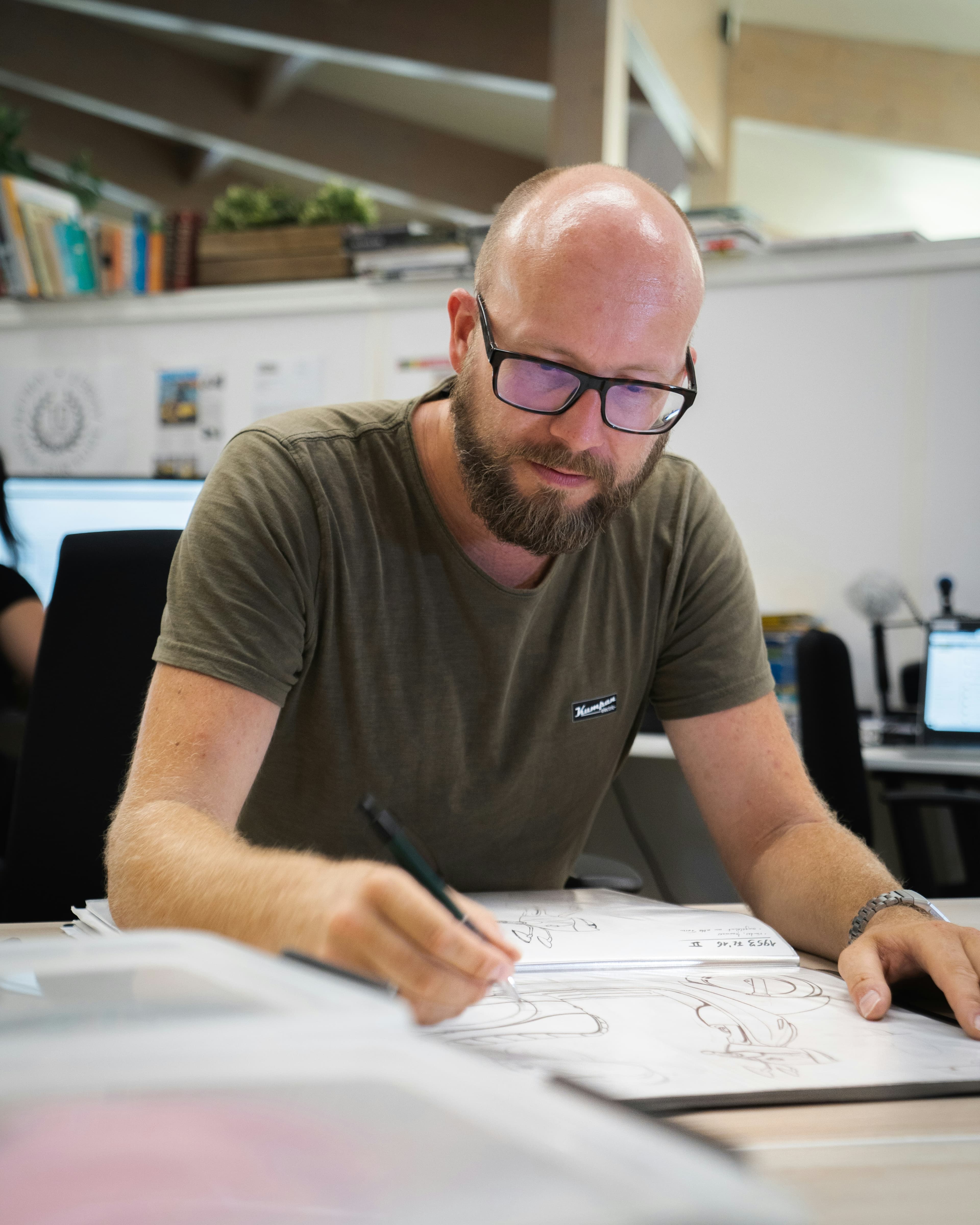 A male furniture designer, bald and wearing glasses